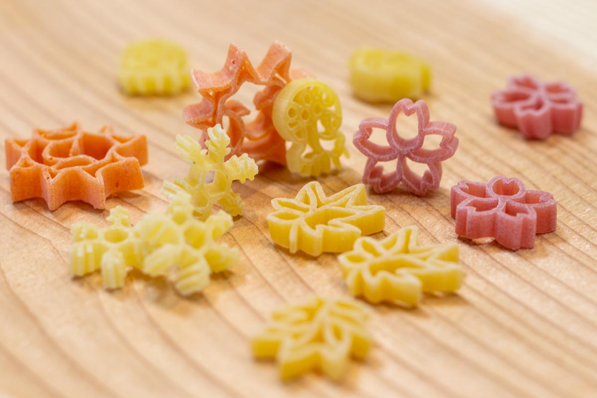 さまざまなショートパスタシリーズ。左はトマト味の「おひさまパスタ」、手前はニンジン味の「月もみじパスタ」。「クラゲ夢パスタ」（中央）は5種類の形。どの商品にも添加物は使用していません。